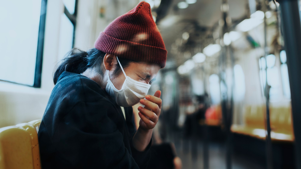 lady wearing a mask coughing on a train