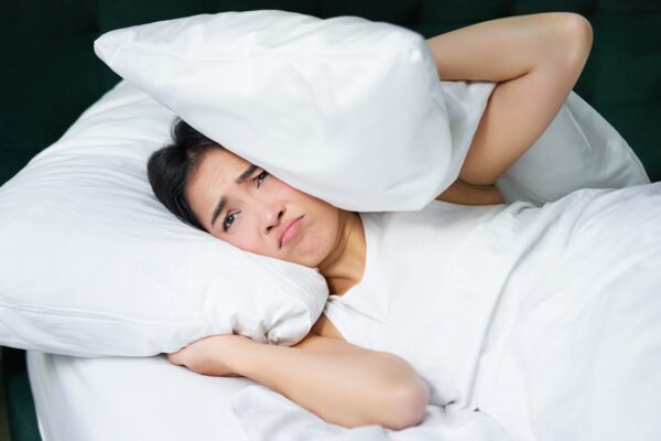 Sad girl with insomnia young asian woman lying in bed cover her ears with pillow cant sleep partner